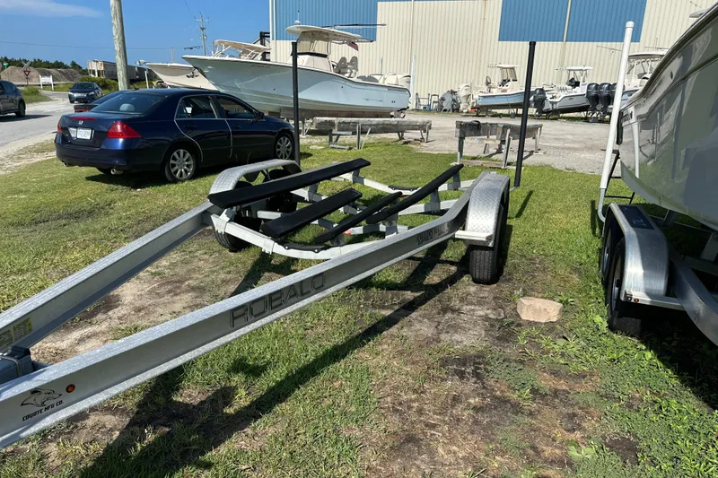 Slide: The Image of Trailer for 2021 Robalo R230 Center Console boat parked on grass near other boats. - 30