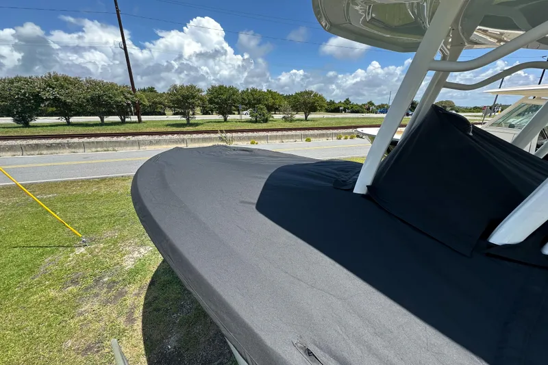 Slide: The Image of 2021 Robalo R230 Center Console boat with black cover, parked outdoors under blue sky. - 33