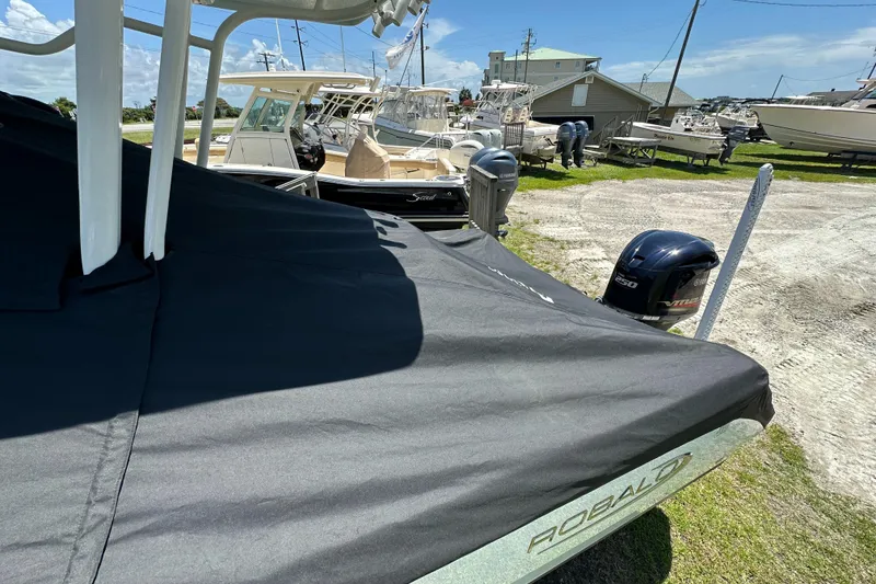 Slide: The Image of 2021 Robalo R230 Center Console boat covered, parked in a marina with other boats. - 34