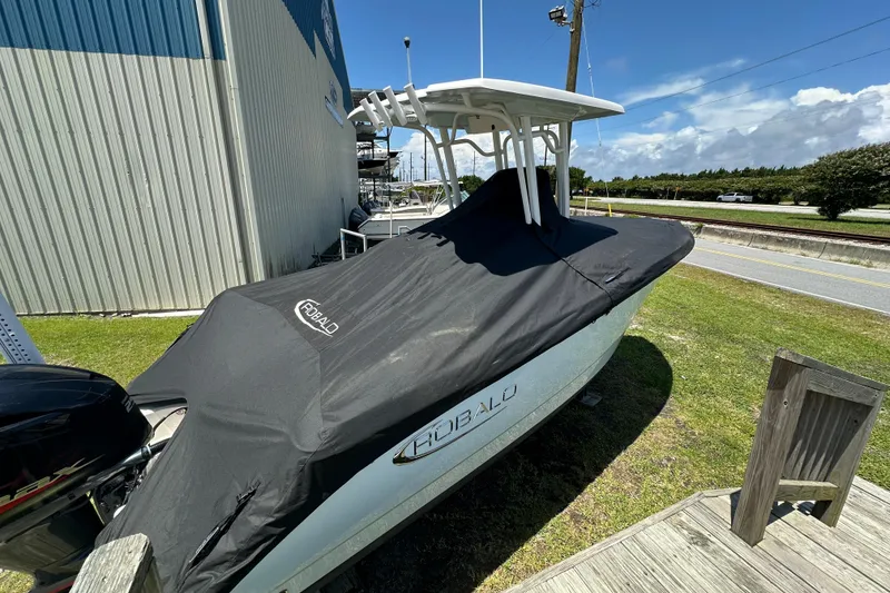 Slide: The Image of 2021 Robalo R230 Center Console boat covered, parked outdoors near a building. - 35