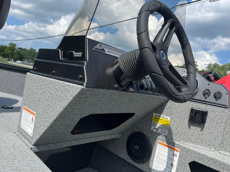 Slide: The Image of 2026 Lund 1775 Adventure SS boat dashboard with steering wheel under a cloudy sky. - 17