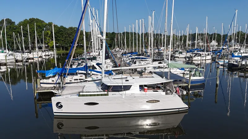 Slide: The Image of 2015 Fountaine Pajot Helia 44 catamaran docked in a marina, surrounded by sailboats. - 2