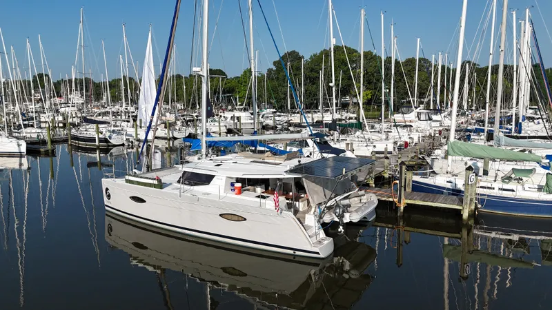 Slide: The Image of Fountaine Pajot Helia 44 catamaran docked in a marina, surrounded by sailboats. - 3