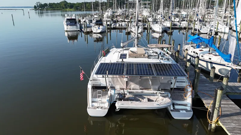 Slide: The Image of 2015 Fountaine Pajot Helia 44 catamaran docked, featuring solar panels and an American flag. - 4