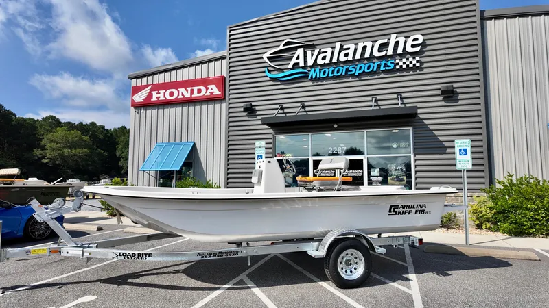 The Image of 2025 Carolina Skiff E18 JVX CC boat on trailer at Avalanche Motorsports dealership. - 1