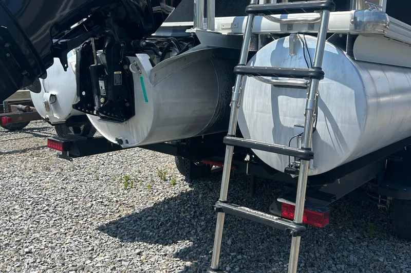 Slide: The Image of 2014 Premier 220 SunSation pontoon boat with ladder and motor, on gravel surface. - 6