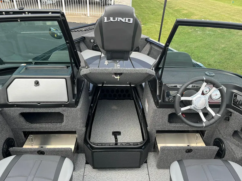 Slide: The Image of 2026 Lund 1775 Impact XS Sport boat interior with open storage compartments and steering wheel. - 14