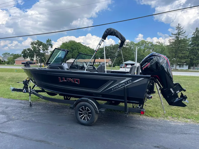Slide: The Image of 2026 Lund 1775 Impact XS Sport boat on trailer, parked outdoors under a blue sky. - 4