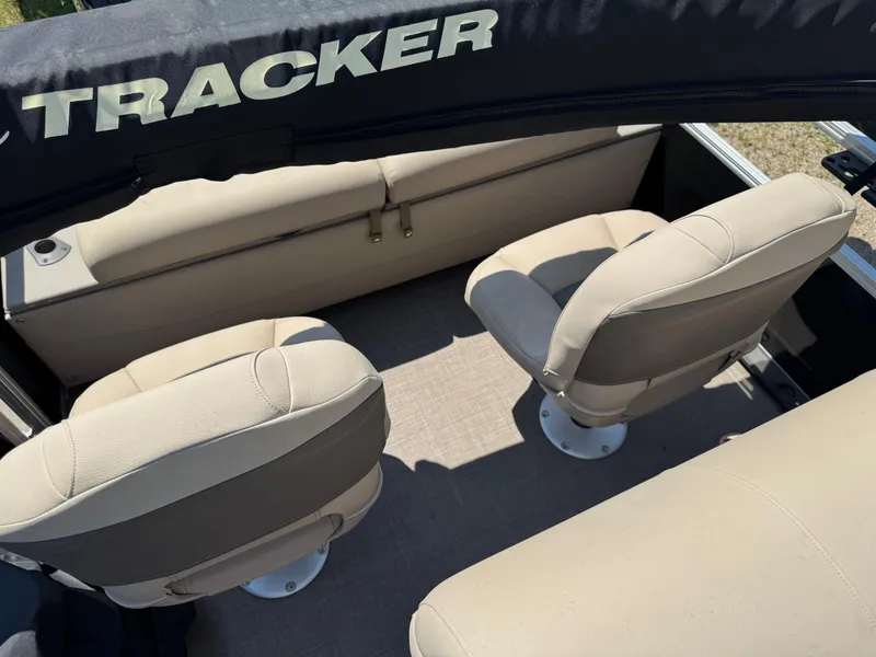 Slide: The Image of 2023 Sun Tracker SportFish 22 DLX boat interior with beige seating and "TRACKER" canopy. - 12
