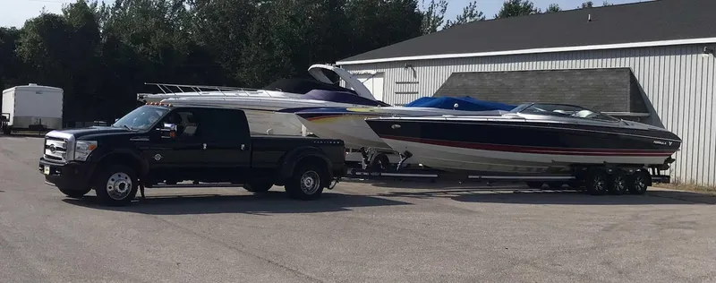 Slide: The Image of Black truck towing 2017 Formula 353 FASTech boat on trailer, parked near a building. - 1