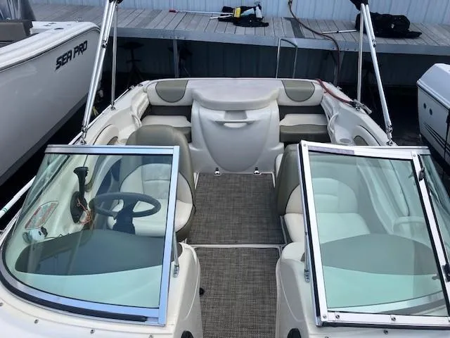 Slide: The Image of 2005 Sea Ray 185 Sport boat interior with seating and steering wheel, docked beside other boats. - 5