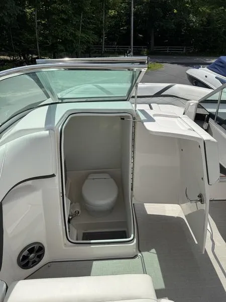 Slide: The Image of 2020 Regal 26 OBX boat interior with open bathroom door, showcasing compact toilet. - 13
