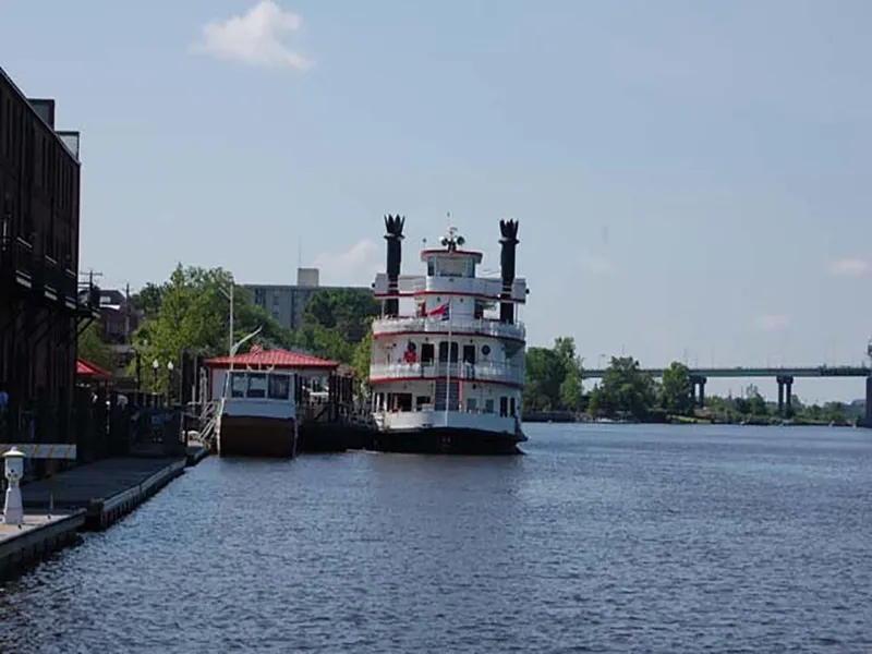 Slide: The Image of Custom 1985 Serodino Dinner Boat docked by riverside with bridge in background. - 3