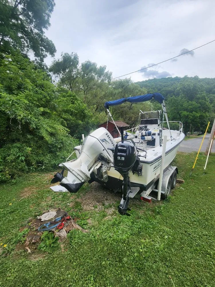 Slide: The Image of 1996 Boston Whaler 21 Outrage boat on trailer, surrounded by lush greenery. - 2