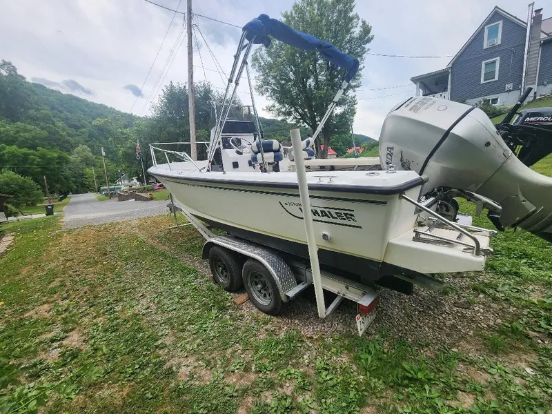 Slide: The Image of 1996 Boston Whaler 21 Outrage boat on trailer, parked in a scenic residential area. - 6