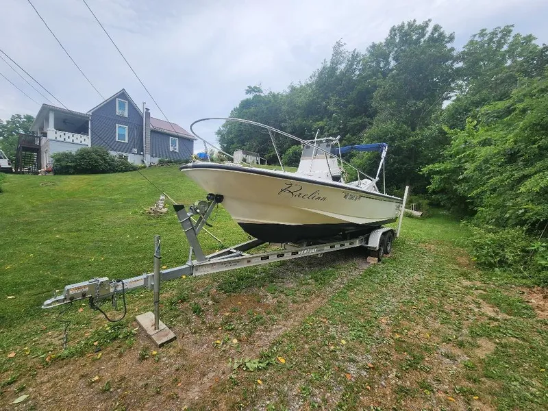 Slide: The Image of 1996 Boston Whaler 21 Outrage boat on trailer, parked on grassy area near house. - 7