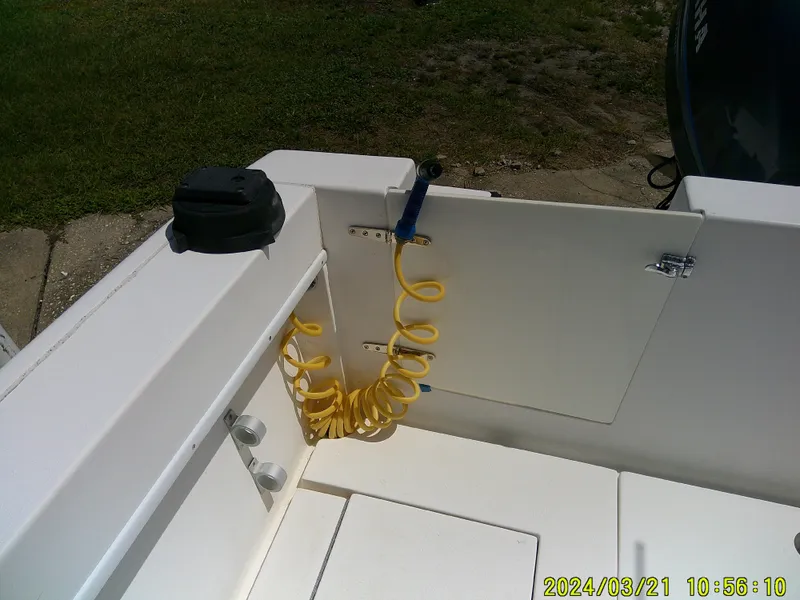Slide: The Image of 2004 Contender 23 Open boat interior with yellow coiled hose and storage compartment. - 16