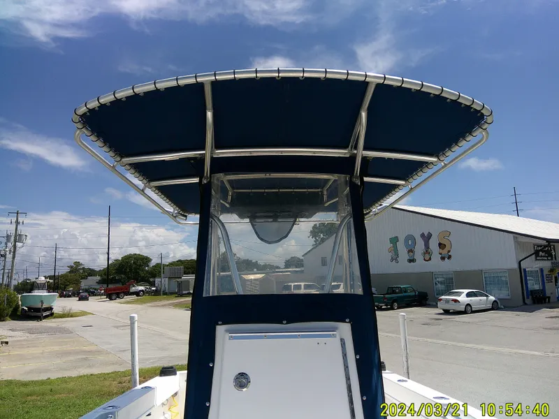 Slide: The Image of 2004 Contender 23 Open boat with T-top, parked near a toy store under a clear sky. - 23