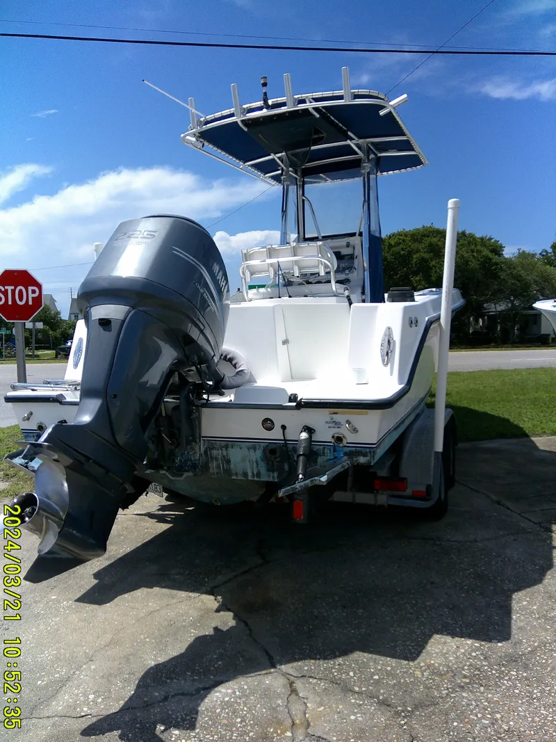 Slide: The Image of 2004 Contender 23 Open boat with outboard motor on a trailer, parked near a stop sign. - 6