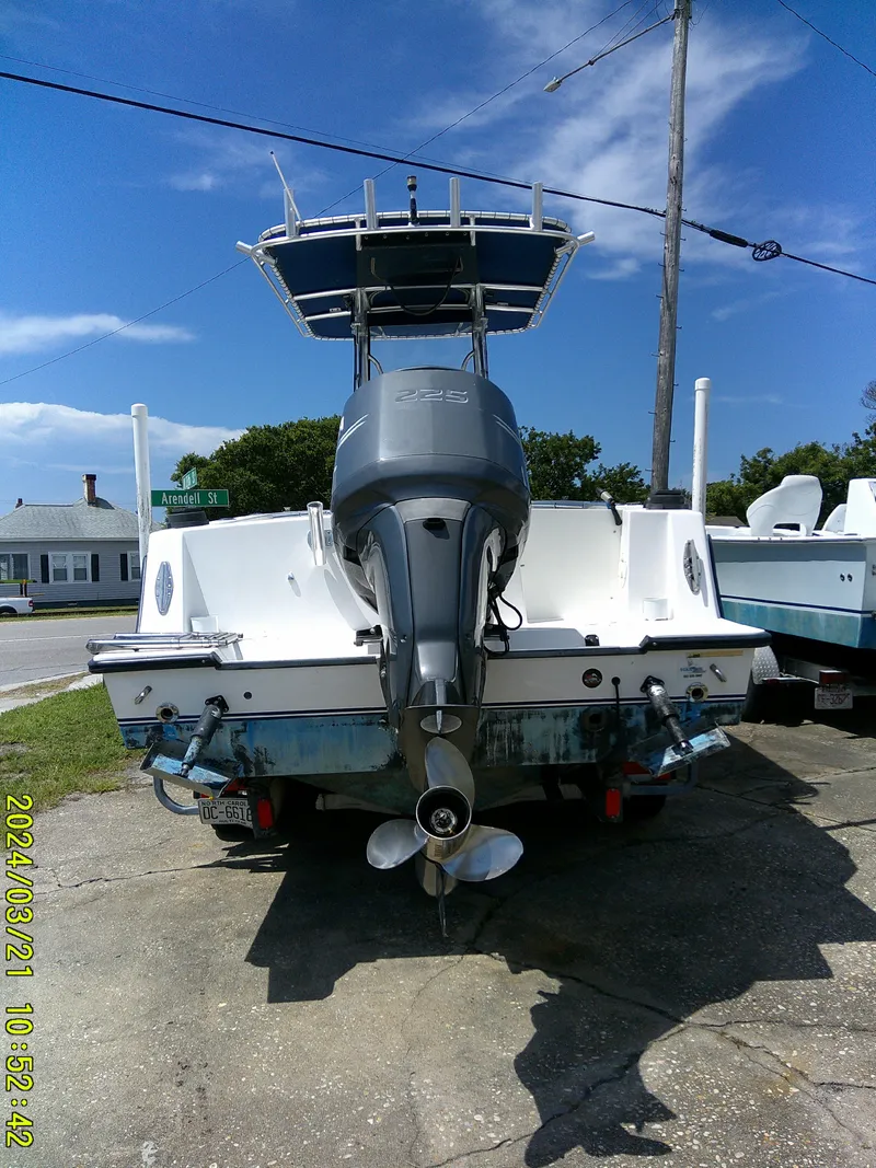 Slide: The Image of 2004 Contender 23 Open boat with outboard motor, parked on a sunny street. - 8