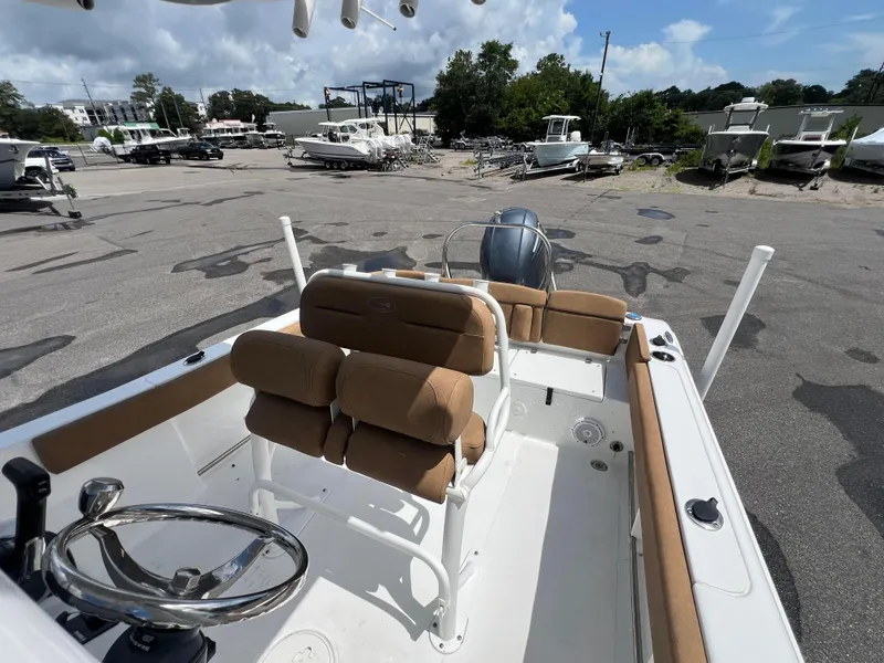 Slide: The Image of 2022 Sea Hunt Ultra 229 boat interior with tan seating and steering wheel, parked outdoors. - 13