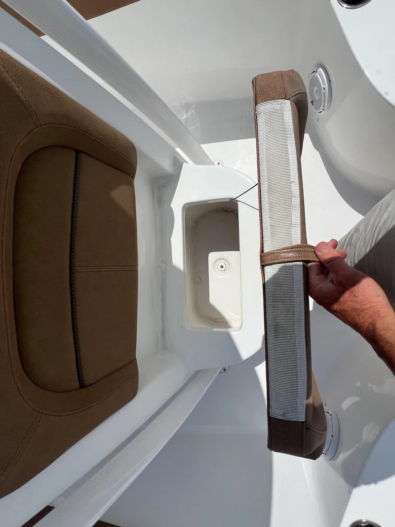 Slide: The Image of 2022 Sea Hunt Ultra 229 boat interior with storage compartment and brown seating. - 9