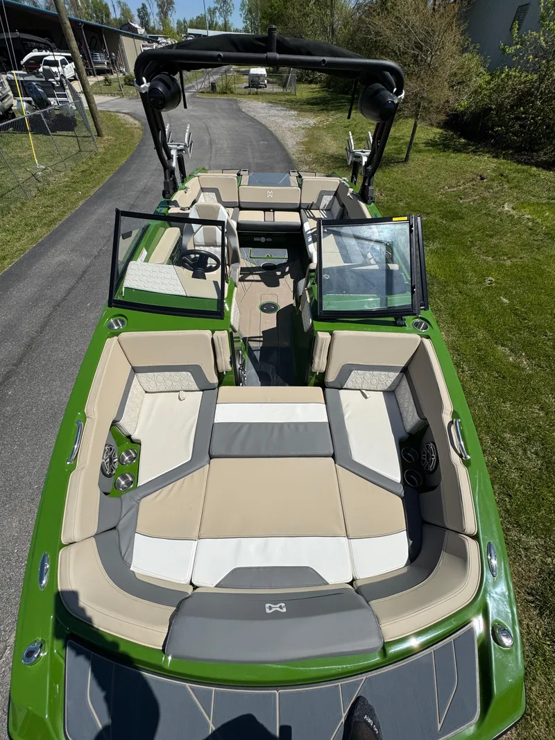 Slide: The Image of 2025 Heyday H22 boat with green exterior and spacious seating, parked on a driveway. - 3