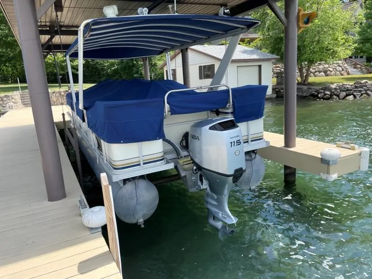 Slide: The Image of 1999 Crest 30 Savannah pontoon boat with Honda 115 engine docked under canopy. - 4