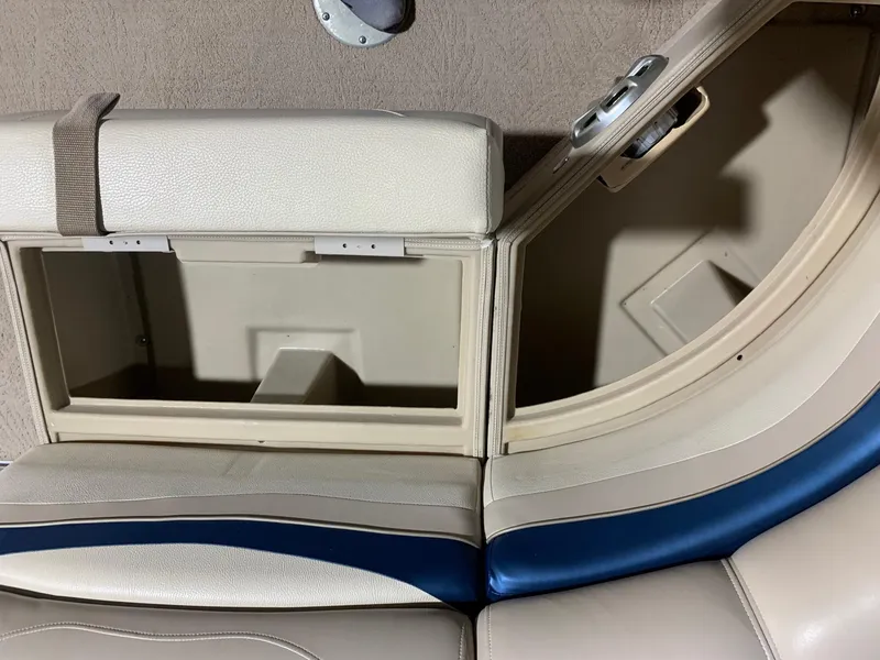 Slide: The Image of Open storage compartment on a 2010 Bennington 2250RCW boat with beige and blue seating. - 22
