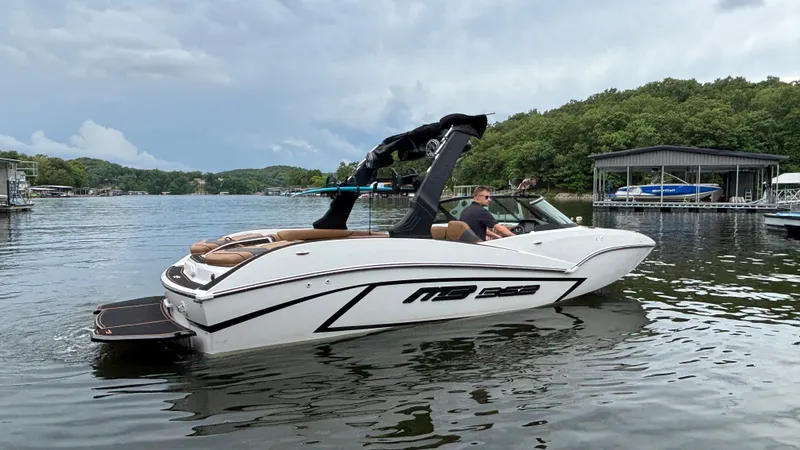 Slide: The Image of 2025 MB B52 23 Alpha boat on a lake, surrounded by trees and docks. - 6