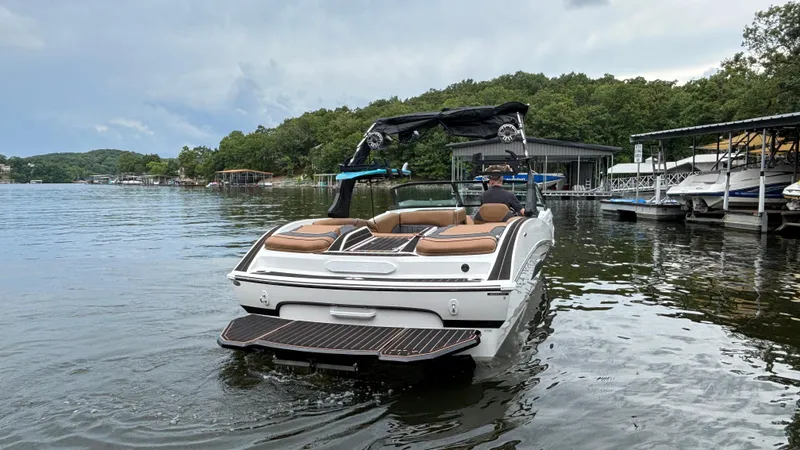 Slide: The Image of 2025 MB B52 23 Alpha boat on a serene lake near docks and lush greenery. - 8