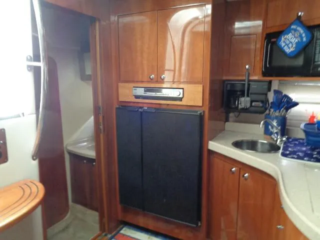 Slide: The Image of 2003 Regal Commodore 3860 yacht interior with wood cabinetry, kitchenette, and compact appliances. - 25
