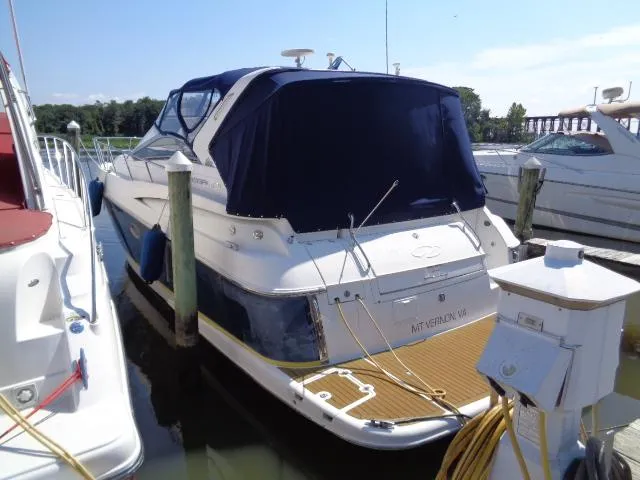 Slide: The Image of 2003 Regal Commodore 3860 yacht docked at marina, featuring blue canopy and white hull. - 3