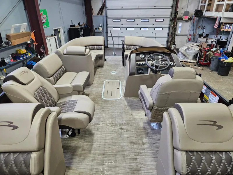 Slide: The Image of 2022 Bennington LX 23 Quad Bench interior with luxurious seating and modern dashboard in a workshop. - 5