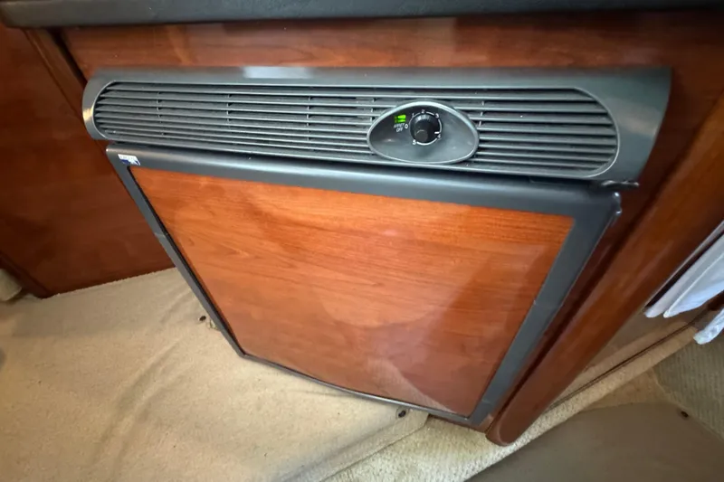 Slide: The Image of 2006 Sea Ray 260 Sundancer cabin refrigerator with wooden finish and control panel. - 29