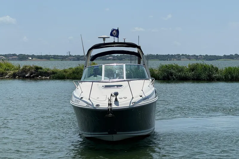 Slide: The Image of 2006 Sea Ray 260 Sundancer boat on calm water, with scenic shoreline background. - 3
