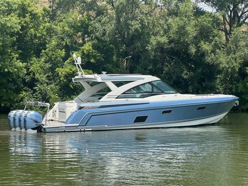 Slide: The Image of 2019 Formula 430 All Sport Crossover boat on calm water, surrounded by lush greenery. - 2