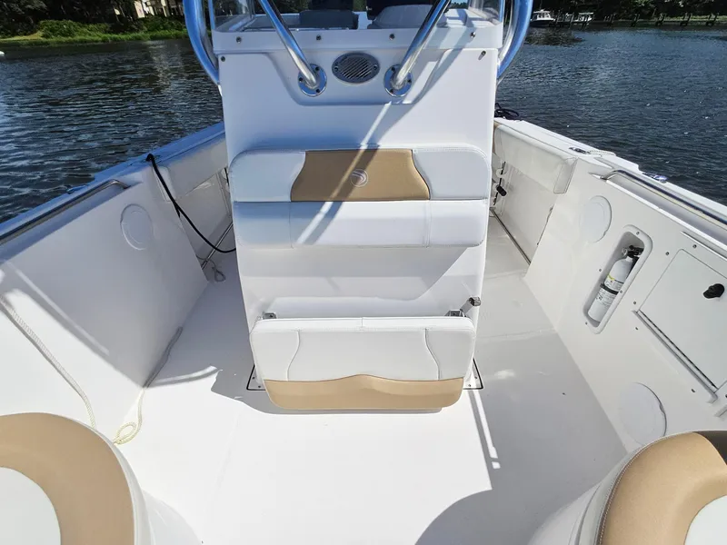 Slide: The Image of 2016 Edgewater 228CC boat interior with seating and storage, on calm water. - 10