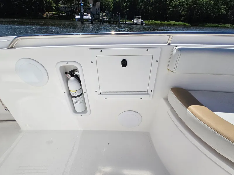 Slide: The Image of 2016 Edgewater 228CC boat interior with fire extinguisher and storage compartment by the water. - 11