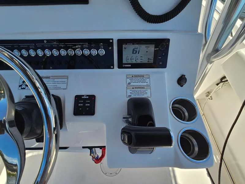 Slide: The Image of 2016 Edgewater 228CC boat dashboard with controls, steering wheel, and cup holders. - 14