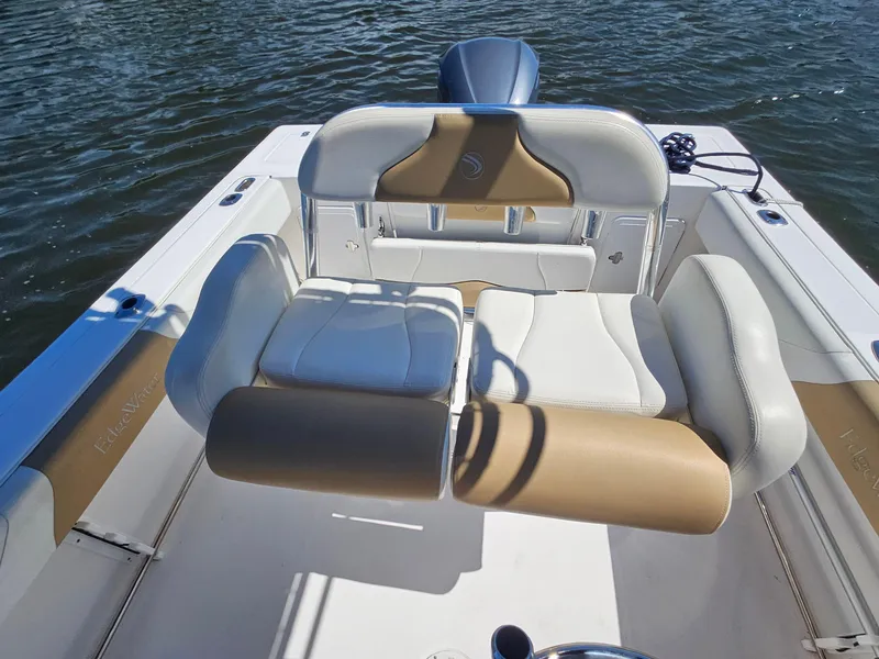 Slide: The Image of 2016 Edgewater 228CC boat interior with cushioned seating, on calm water. - 15