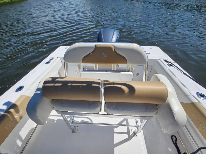 Slide: The Image of 2016 Edgewater 228CC boat interior with tan and white seating on calm water. - 16