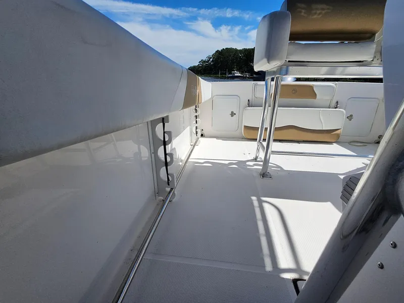 Slide: The Image of 2016 Edgewater 228CC boat interior with seating and storage, under a clear blue sky. - 25