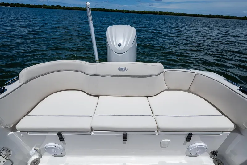 Slide: The Image of 2024 Sea Hunt Ultra 239 SE boat with cushioned seating, on calm water. - 13