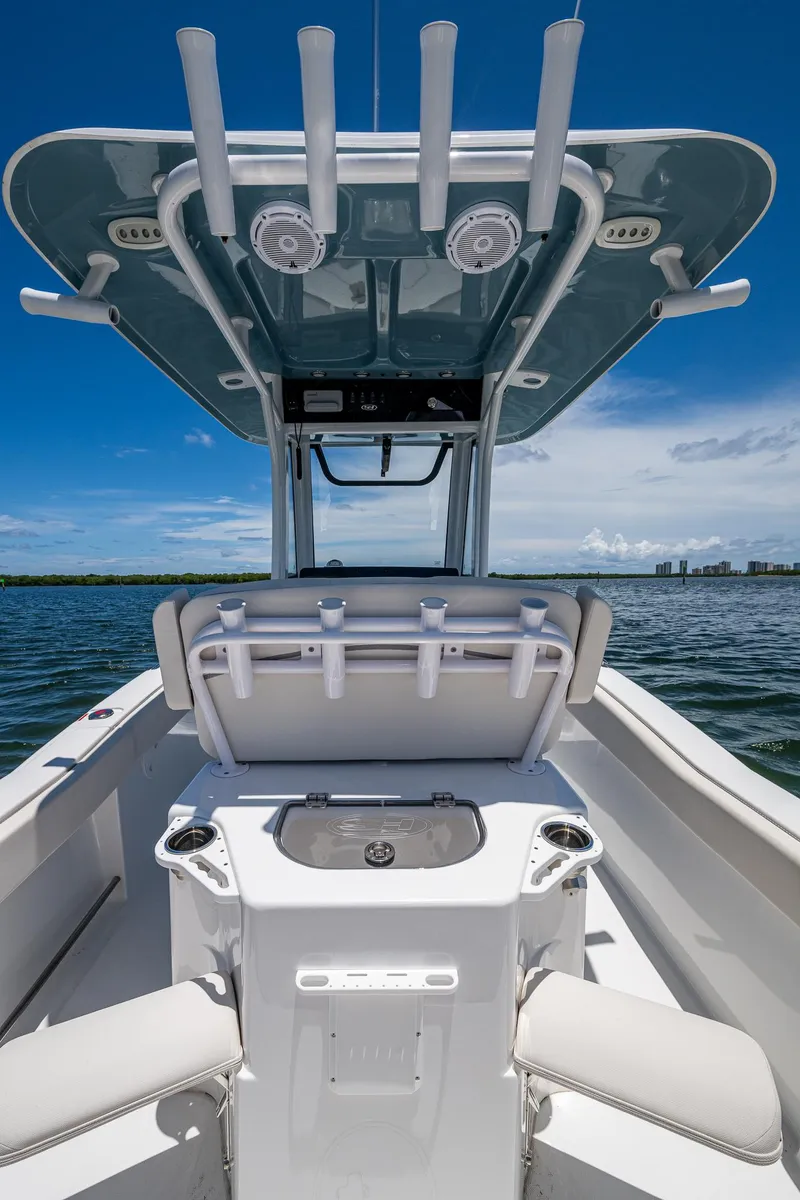 Slide: The Image of 2024 Sea Hunt Ultra 239 SE boat interior with rod holders and seating, under a clear blue sky. - 18