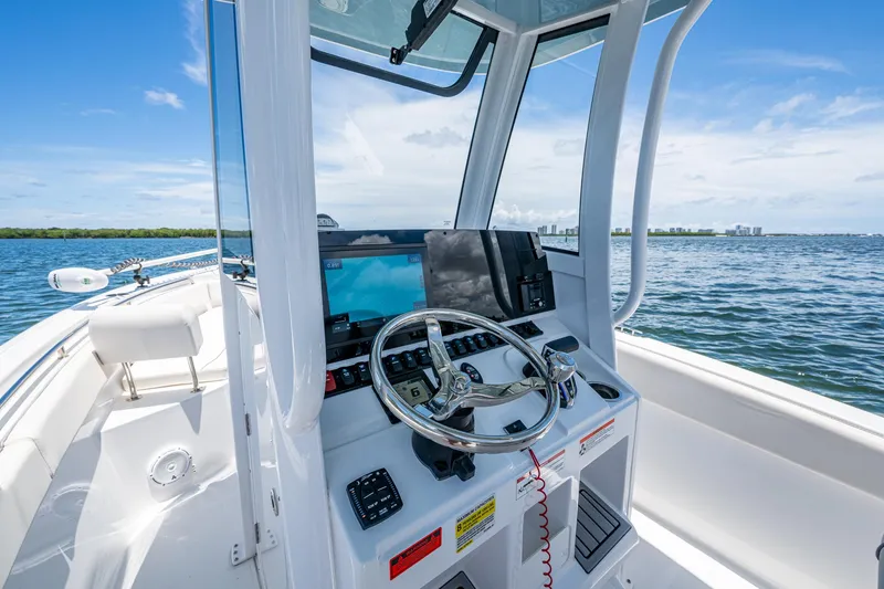 Slide: The Image of 2024 Sea Hunt Ultra 239 SE boat dashboard with steering wheel, on open water. - 26