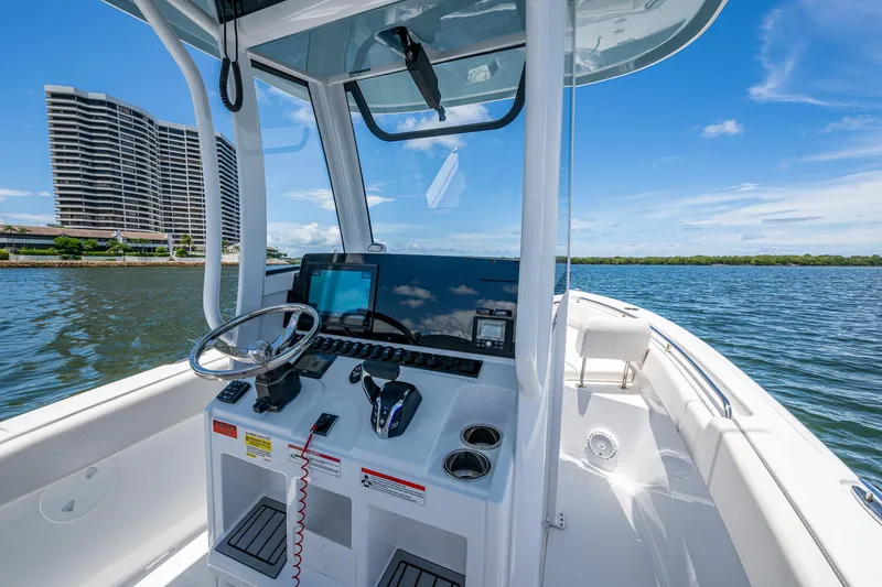 Slide: The Image of 2024 Sea Hunt Ultra 239 SE boat interior with steering console, on a sunny day near waterfront buildings. - 27
