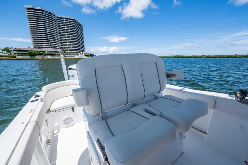 Slide: The Image of 2024 Sea Hunt Ultra 239 SE boat interior with plush seating, overlooking water and modern architecture. - 29