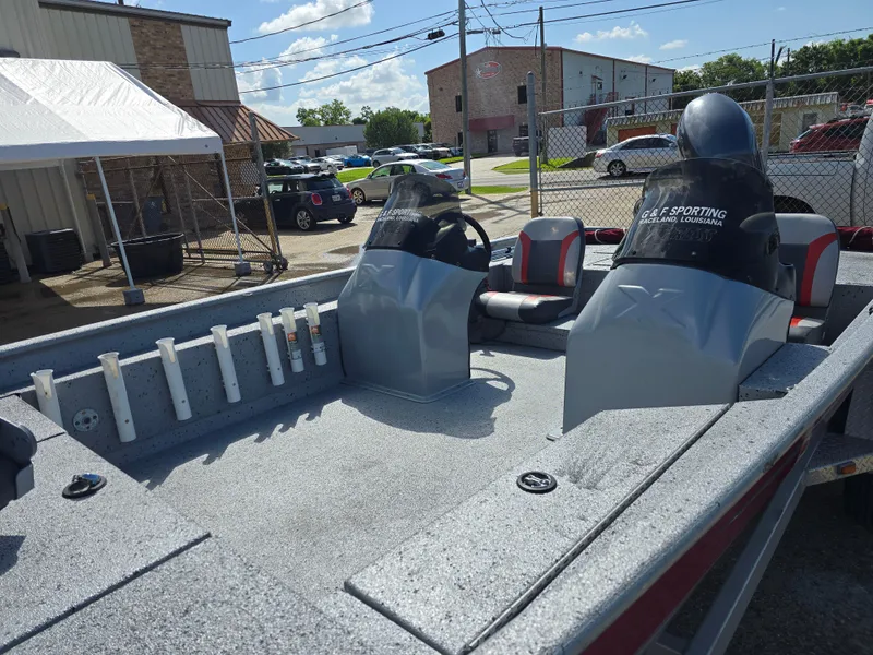 Slide: The Image of 2014 Xpress XP200 boat interior with dual consoles and rod holders, parked outdoors. - 10