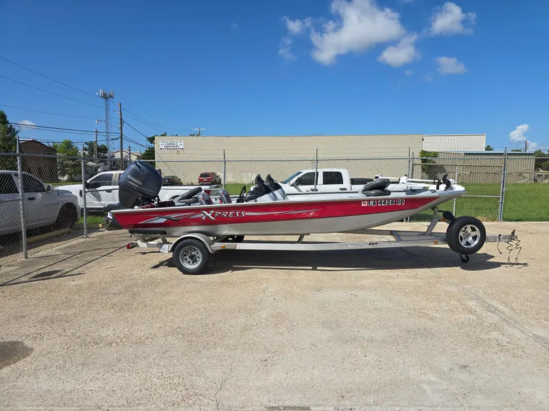 Slide: The Image of 2014 Xpress XP200 boat on trailer, parked outdoors under clear blue sky. - 2